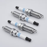 Set of four spark plugs for Toyota Prius V 2016 ZVW50, with metal threaded body, white ceramic insulator, and black tip, used for engine ignition.